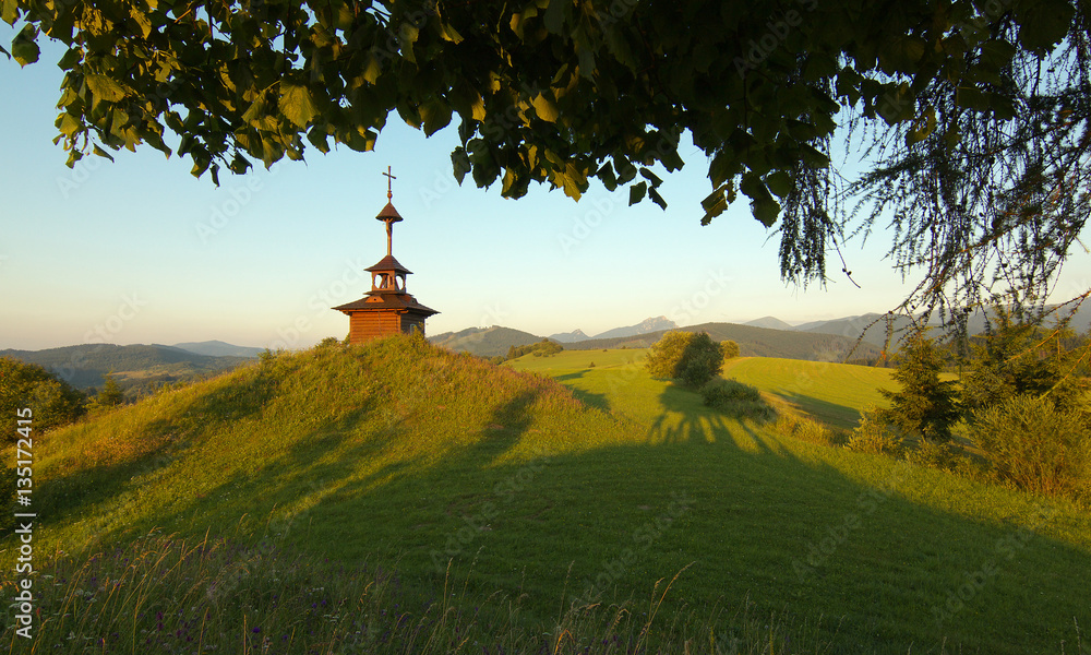 View of a meadow with a small chapel and mountains  in Slovakia