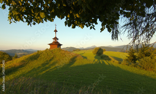 View of a meadow with a small chapel and mountains  in Slovakia photo