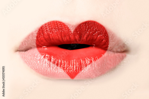 Red heart painted on woman lips close up, valentines day concept