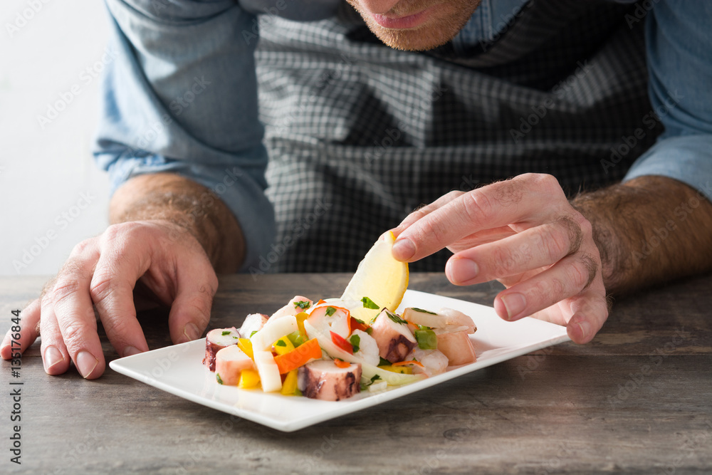Chef preparing seafood ceviche on wooden table

