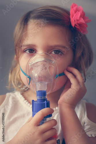 Little girl using inhaler. photo