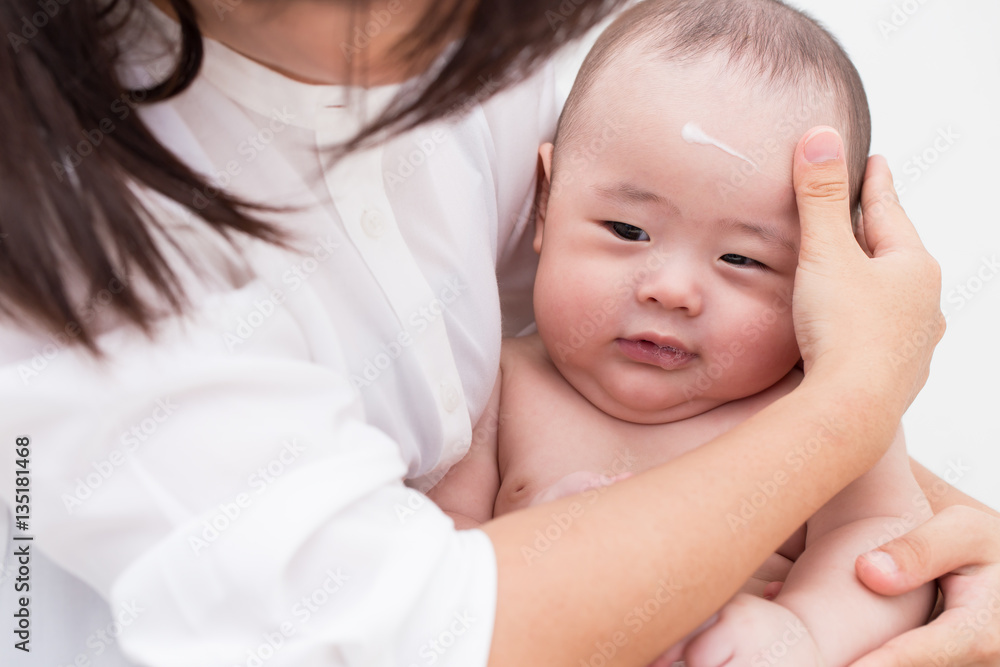 Mother applying baby lotion for son Mother applying baby lotion for son