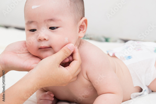 Mother applying baby lotion for son