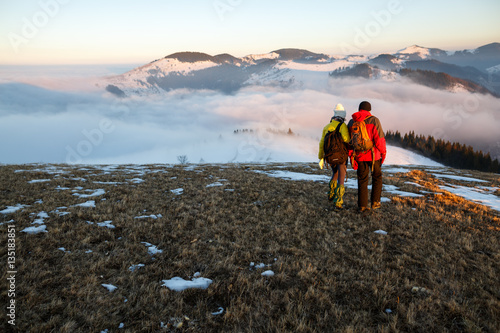 Young couple hiking outdoors with backpacks in winter mountains