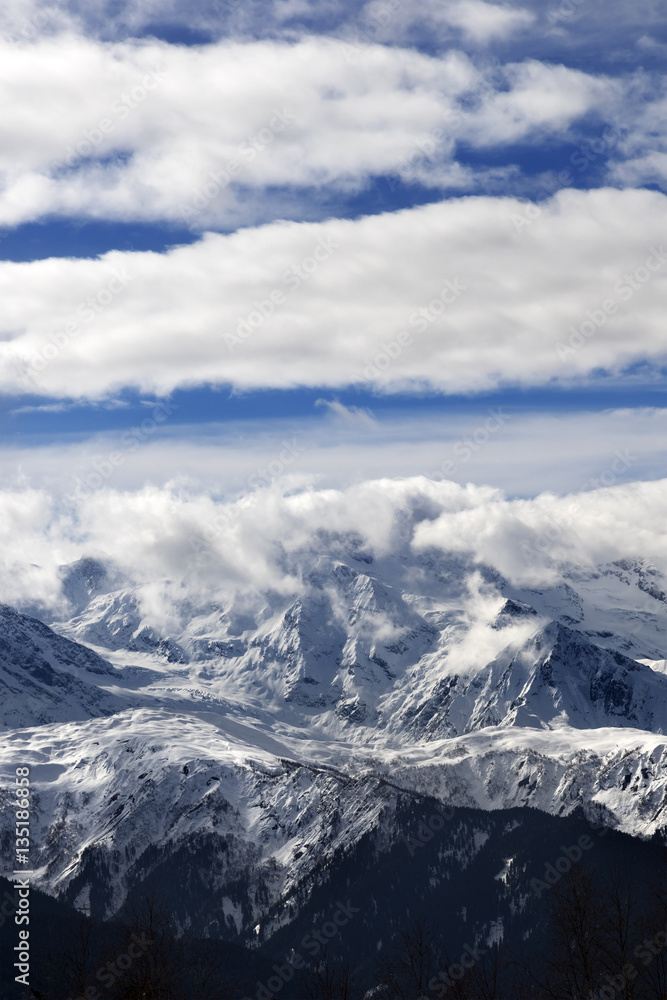 Naklejka premium View on snow mountains and sunlight cloudy sky at winter day