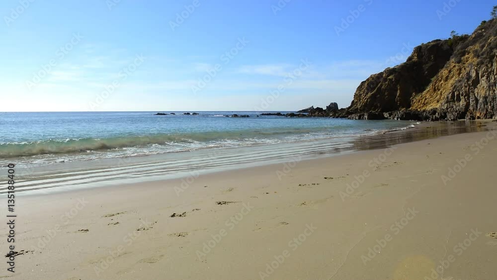A bright, sunny day along the sandy shore of a scenic cove in Laguna Beach, California with beautiful, calm ocean water. A bright, sunny day along the sandy shore of a scenic cove in Laguna Beach, California with beautiful, calm ocean water.