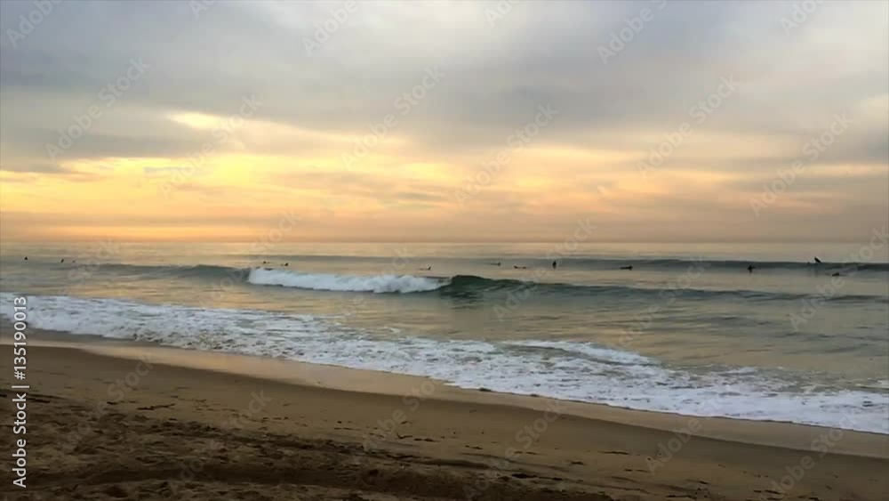 Medium perspective of a beautiful beach and ocean waves in Huntington Beach, California framed against a pastel sunrise. Medium perspective of a beautiful beach and ocean waves in Huntington Beach, California framed against a pastel sunrise.