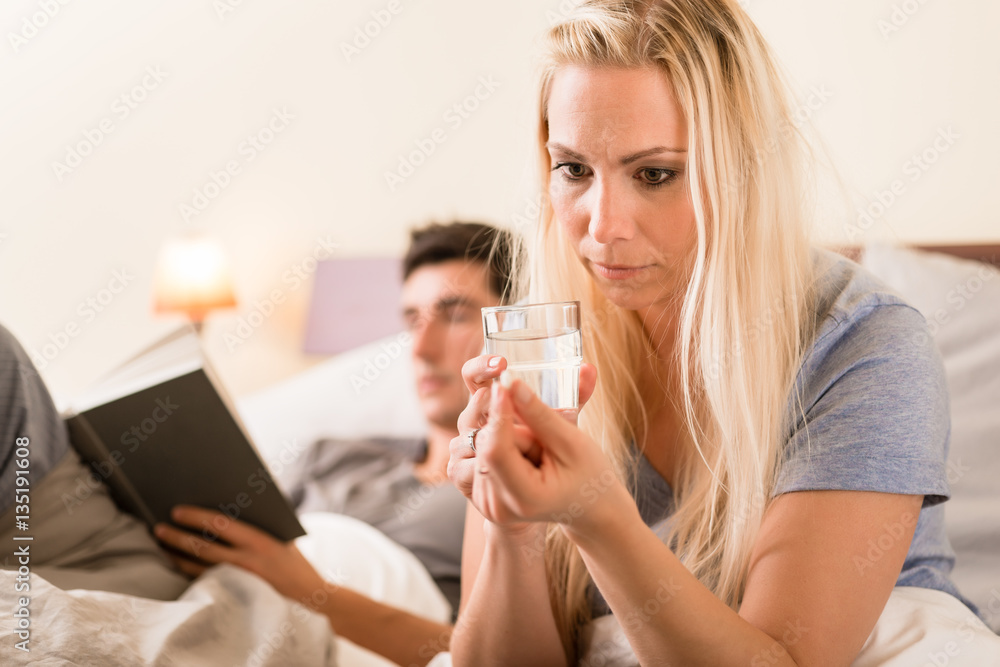 Worried woman taking a pill before sleep at night Worried woman taking a pill before sleep at night