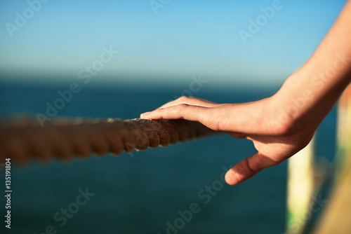 young woman hand holding rope on the bridge, horizontal