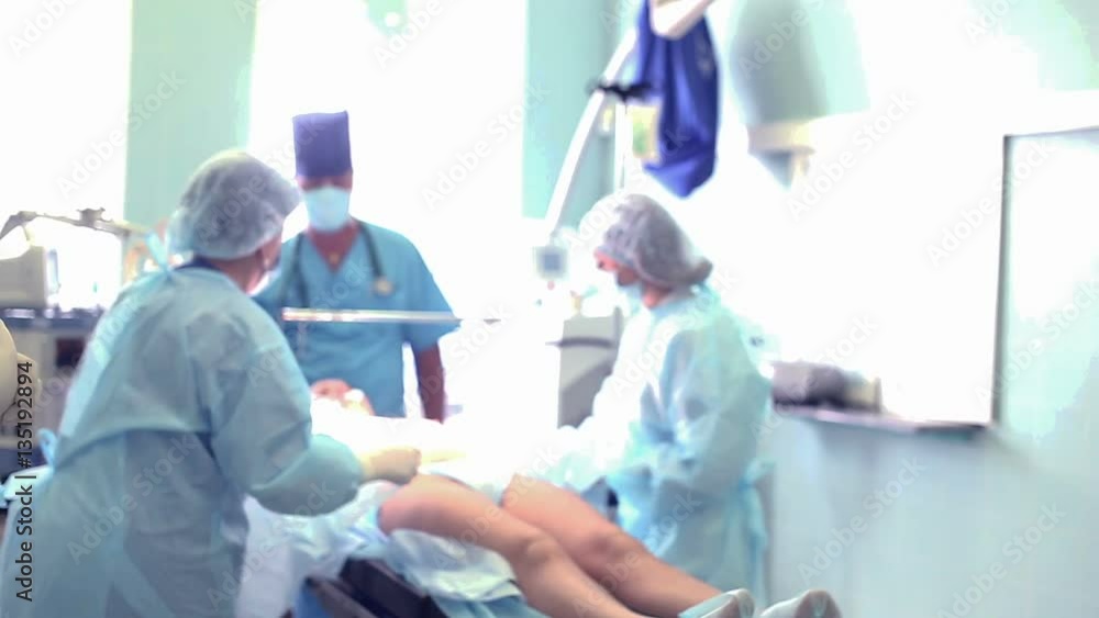 Surgical team preparing a patient for cosmetic plastic surgery on breasts in hospital operating room. Surgeon doctor getting ready to operate. Breast implant augmentation surgery. Mammaplasty. Surgical team preparing a patient for cosmetic plastic surgery on breasts in hospital operating room. Surgeon doctor getting ready to operate. Breast implant augmentation surgery. Mammaplasty.