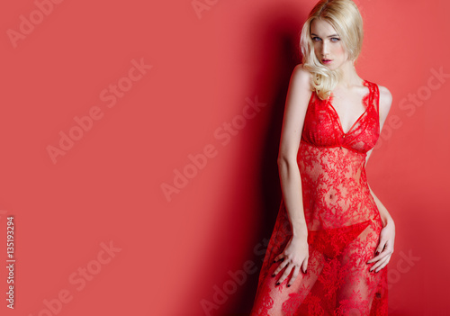 Fotografía sexy blonde girl in red lace lingerie posing in the studio on a red background