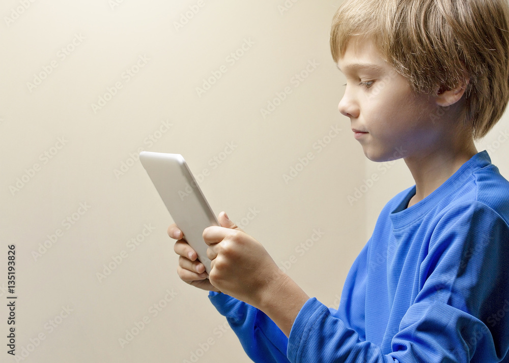 Fototapeta premium Child looking at digital tablet computer and playing online games, learning or reading. Close up