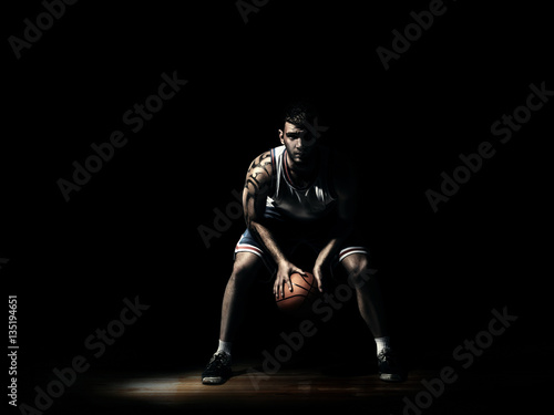 basketball player in durkness on parquet with ball