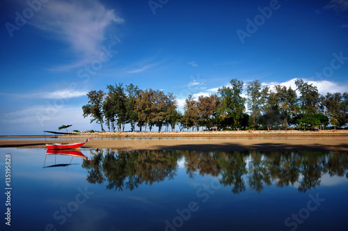 Kuala Ibai Lagoon, Terengganu, Malaysia.  showing an amazing view of small red boat,  texture and symmetrical reflections in water. photo
