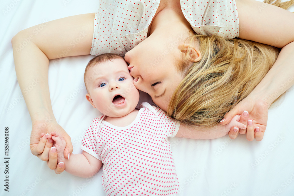 Mother kisses baby lying on the bed closeup. Mother kisses baby lying on the bed closeup.