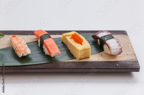 Sushi Set Include Shrimp, Kani, Tamagoyaki with Squid Served on Leaf on Stone Plate.