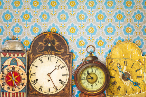 Colorful vintage clocks in front of retro wallpaper