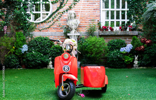 Vintage small red scooter with sidecar in the garden