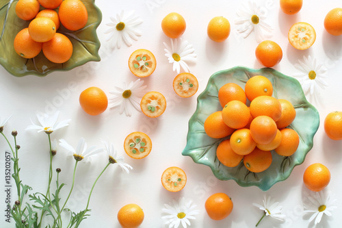 Fresh kumquat and marguerite flower on white background photo