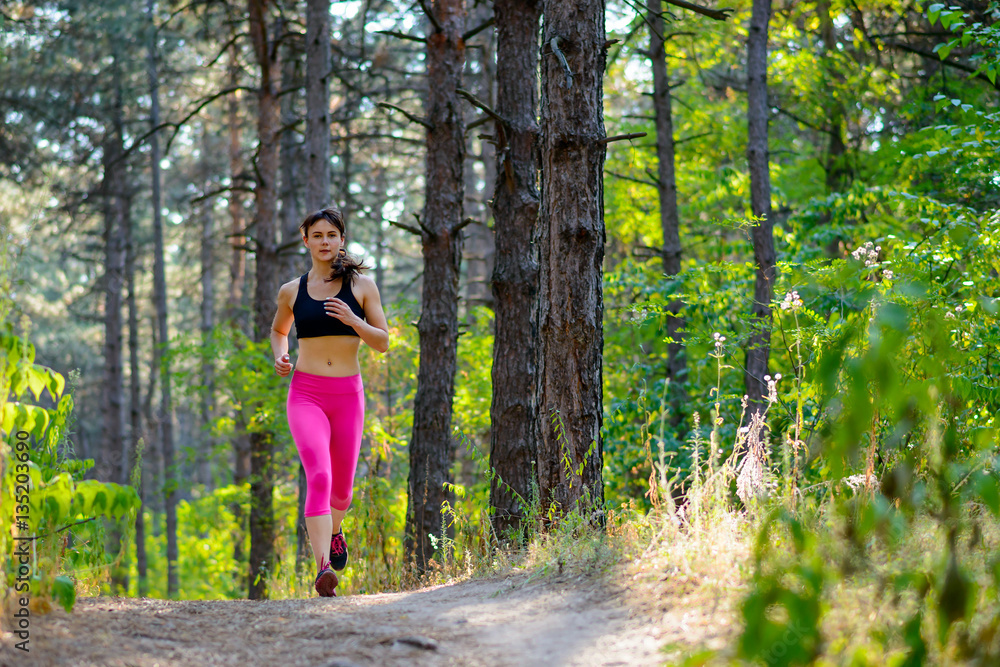 Young Woman Running on the Trail in the Beautiful Wild Forest. Active Lifestyle Concept. Space for Text. Young Woman Running on the Trail in the Beautiful Wild Forest. Active Lifestyle Concept. Space for Text.