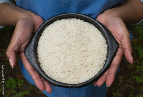 hands holding rice in a bowl