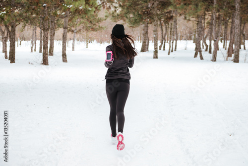 Back view of fitness woman running in a city park