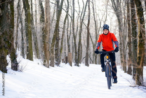 Mountain Biker Riding Bike on the Snowy Trail in Beautiful Winter Forest