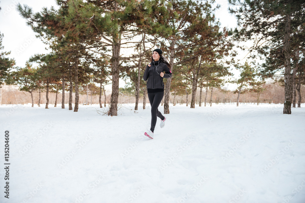 Beautiful young woman running in the winter forest