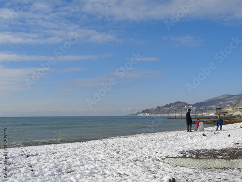 Family making snowman on snowy beach, coast Sochi, Russia