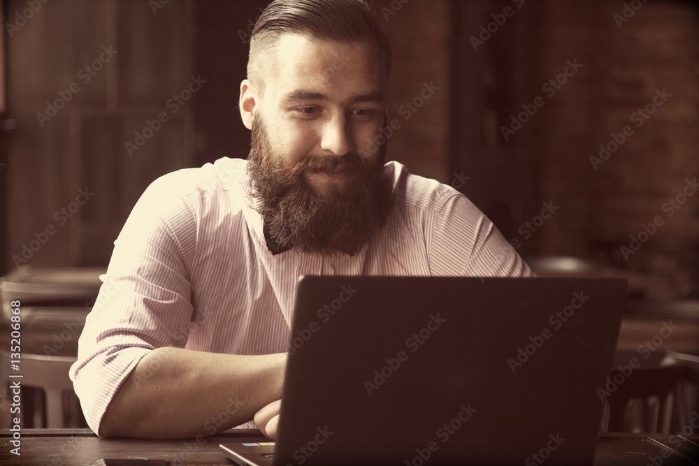 Portrait of a young bearded businessman working with laptop (Suc Portrait of a young bearded businessman working with laptop (Suc