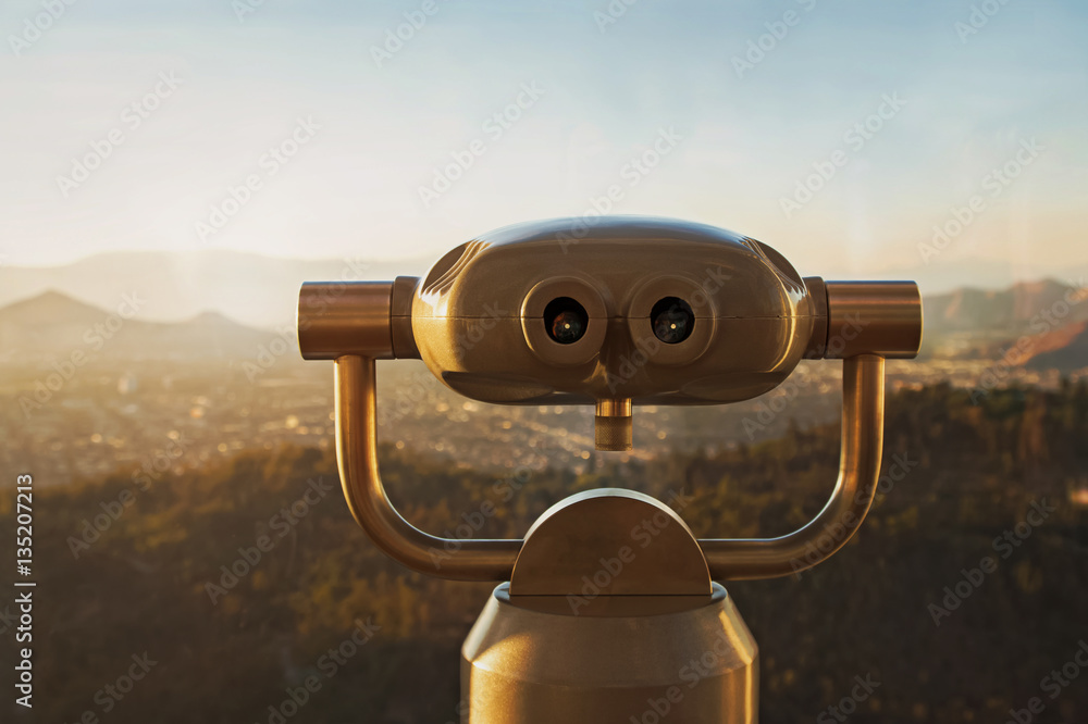 Touristic telescope on the blurred city background