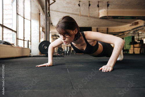 Fototapeta Naklejka Na Ścianę i Meble -  Fitness woman working out and doing pushups in gym