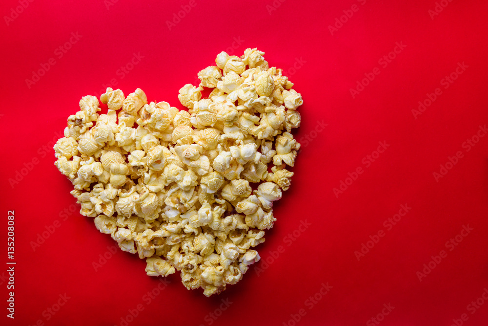 Cinema concept of popcorn arranged in a heart shape on red backg Cinema concept of popcorn arranged in a heart shape on red backg