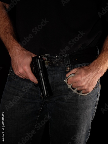 Gun brass knuckles in the hand on black