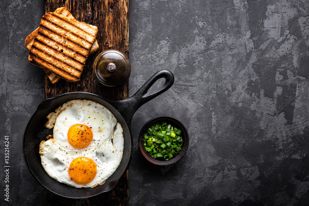 fried eggs on dark background with space for text - obrazy, fototapety, plakaty 