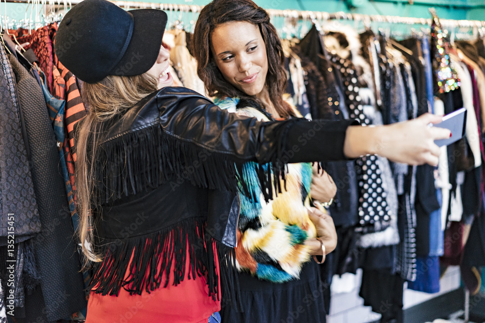 Fototapeta premium two female mixed race friends buying clothes in a store