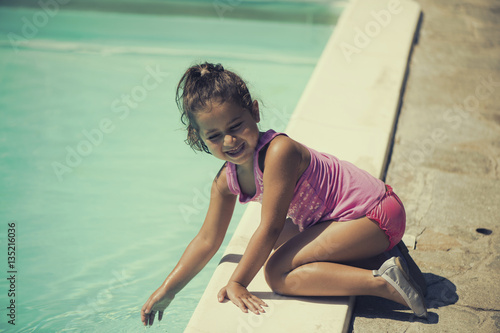 The little Italian girl playing near the pool in the summer