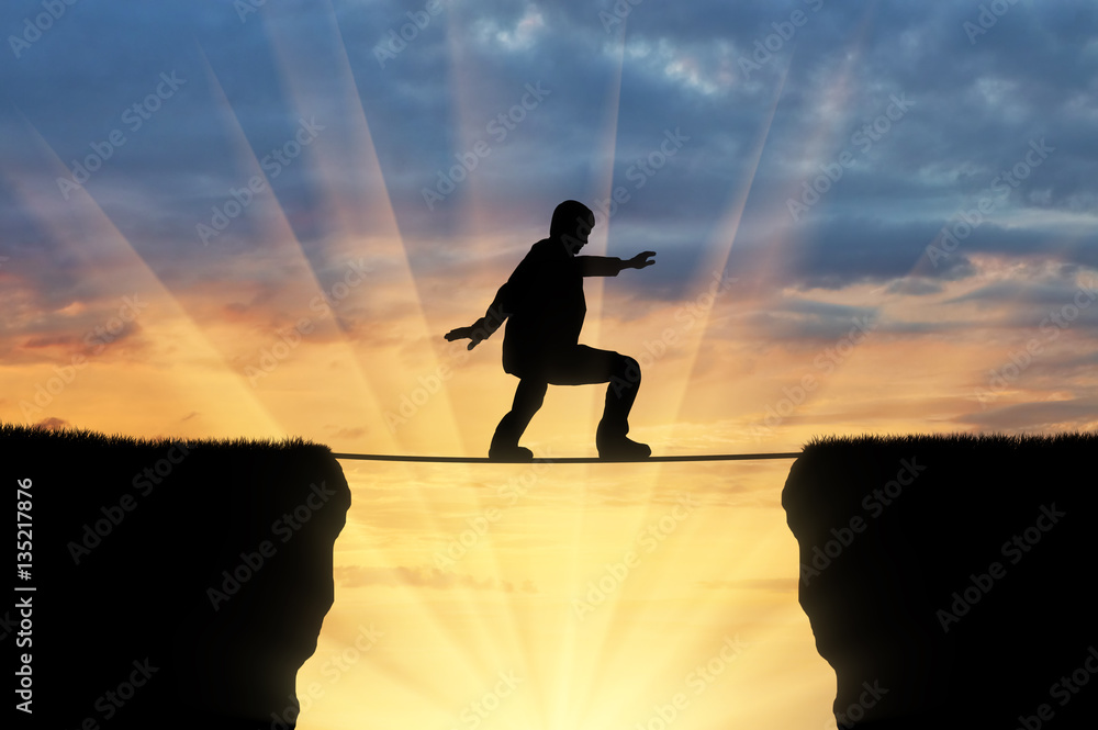 Man walks on a tightrope over a cliff Stock Photo