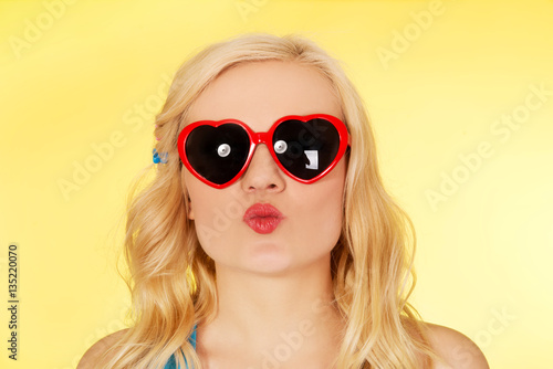 Young woman in sunglasses blowing lips kiss 