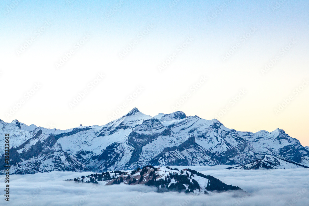 Swiss mountain range with clouds during sunrise near Gstaad, Bernese Oberland, Switzerland