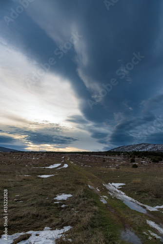 The road into the sunset across the field on a background of dramatic sky. Russia, Stary Krym.