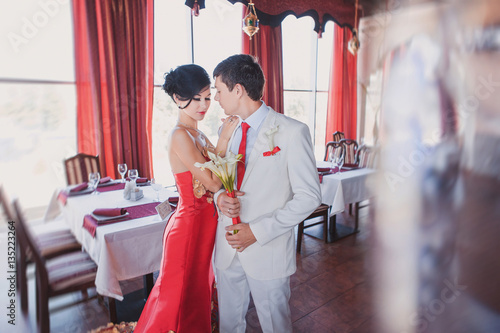 Bride in red wedding dress and groom with red tie at wedding day