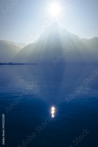  Shape in nature. Sunrays over the top of the mountains reflected in the lake. Play of light and shadow creates volume pyramid shape.