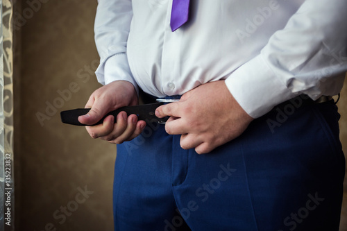 man putting on a belt  Businessman  Politician  man s style  male hands closeup  American businessman  European businessman  a businessman from Asia  People  business  fashion and clothing concept