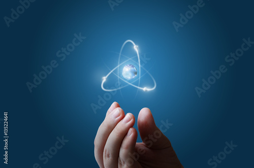 Slika na platnu Atoms flying along the orbit in the hand.