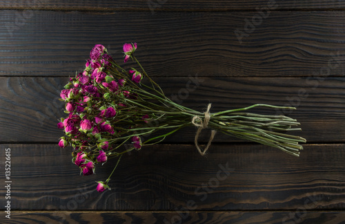 Bouquet of dry flowers with ribbon on dark wooden surface
