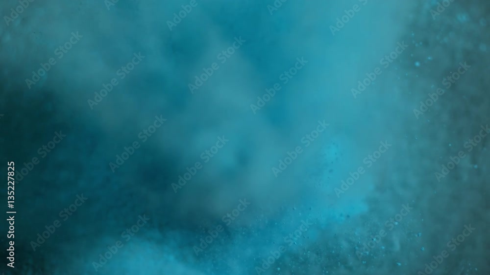 Blue holi powder bounces off black canvas background, slow motion closeup Blue holi powder bounces off black canvas background, slow motion closeup