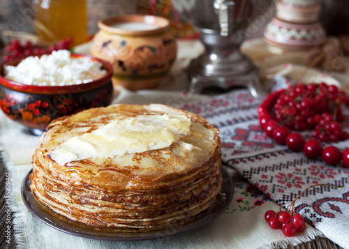 Traditional Ukrainian or Russian pancakes with cottage cheese and sour cream on napkins with embroidery. Traditional dishes on the holiday Carnival Maslenitsa Shrovetide.