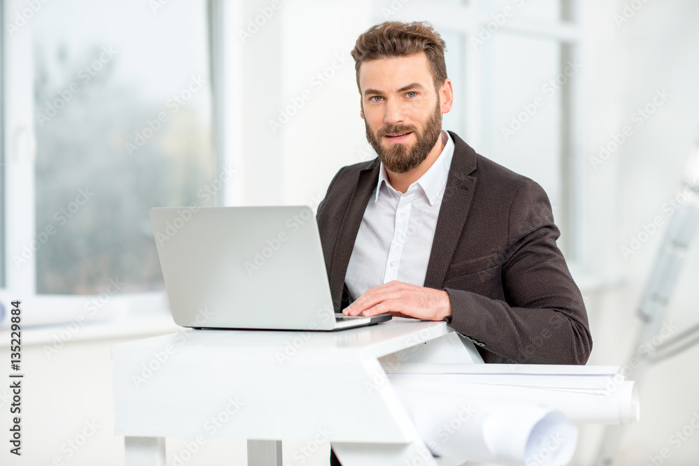 Architect or designer working with laptop on the ladder with paper drawings in the bright room for renovating Architect or designer working with laptop on the ladder with paper drawings in the bright room for renovating