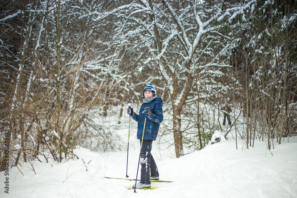 young boy with ski in the snow forest.